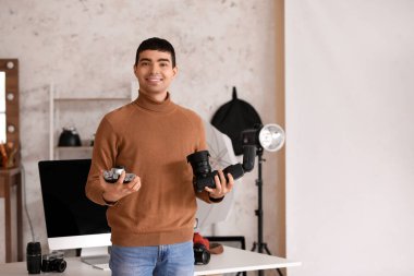 Stüdyoda kameraları olan genç bir erkek fotoğrafçı