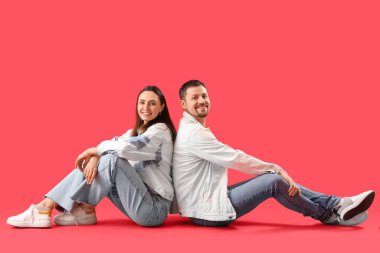 Kırmızı arka planda oturan mutlu genç çift