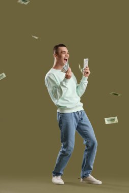 Yeşil arka planda dolar banknotları olan mutlu genç adam.