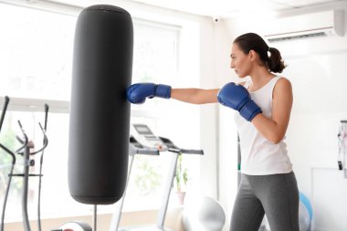 Spor salonunda kum torbasıyla antrenman yapan genç bir kadın. Nefsi müdafa kavramı