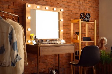 Soyunma odasında şık bir ayna, giysi askısı ve makyaj malzemesi olan bir masa.