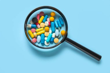 Mavi arka planda farklı haplar içeren büyüteç