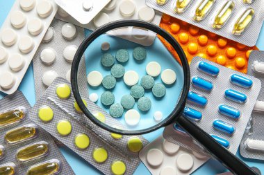 Mavi arka planda farklı haplar içeren büyüteç