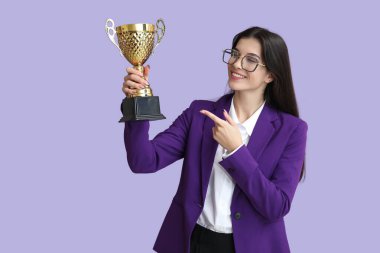 Leylak arka planında altın bardağı gösteren genç bir iş kadını.