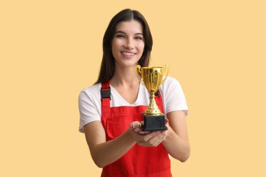 Sarı arka planda altın bardaklı kadın işçi.