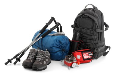 Sırt çantalı kamp malzemeleri, yürüyüş direkleri ve beyaz arka planda taşınabilir soba seti.