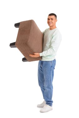 Genç adam beyaz arka planda pouf taşıyor.