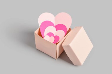 Gri zemin üzerinde kağıt kalpler olan hediye kutusu