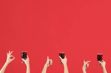 Kırmızı arka planda sıcak şarap kadehleriyle kadın elleri.