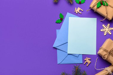 Zarflı boş kağıt, Noel süsü ve mor arka planda hediyeler. Noel Baba 'ya mektup
