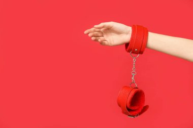 Kırmızı arka planda seks dükkanından kelepçeli bir kadın.