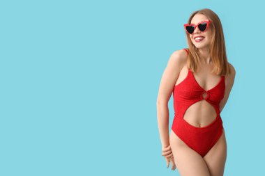 Mavi arka planda, tank mayo giymiş güzel bir kadın.