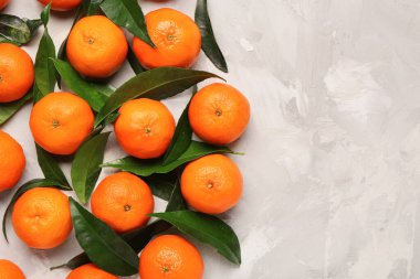 Gri arkaplanda tatlı mandalinalar ve yapraklar