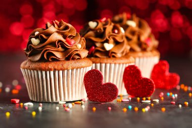 Gri grunge masasında Sevgililer Günü için pullu ve kalpli lezzetli çikolatalı kekler.