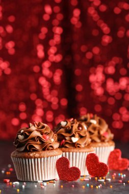 Gri grunge masasında Sevgililer Günü için pullu ve kalpli lezzetli çikolatalı kekler.