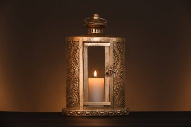 Ramazan ayı için yanan mumlu Müslüman lambası koyu kahverengi arka planda.