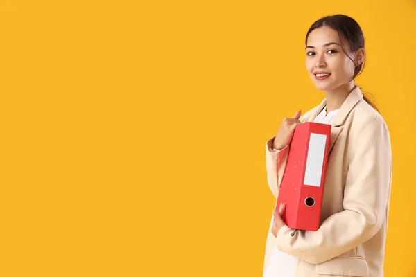 Young Asian businesswoman with document folder on yellow background