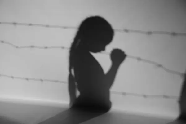 Shadow of little Jewish girl and barbed wire on grey background. International Holocaust Remembrance Day