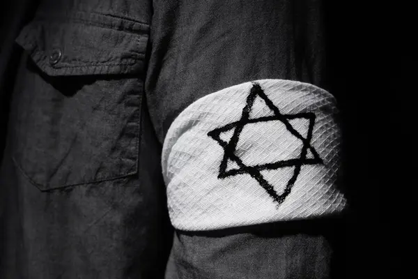 Young Jewish man with armband on black background, closeup. International Holocaust Remembrance Day
