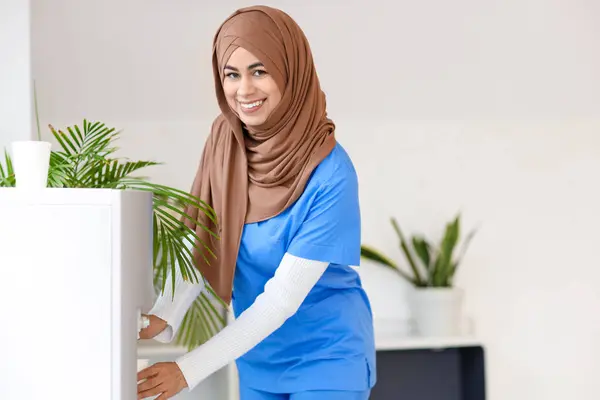 Pasante Médica Musulmana Hembra Vertiendo Agua Del Refrigerador Clínica —  Fotos de Stock