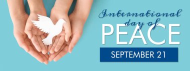 Açık mavi arka planda kağıt güvercini olan anne ve çocuğun elleri. Uluslararası Barış Günü Sancağı 