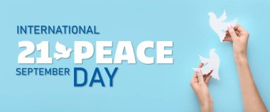 Açık mavi zemin üzerinde kağıt güvercinler olan eller. Uluslararası Barış Günü Sancağı 