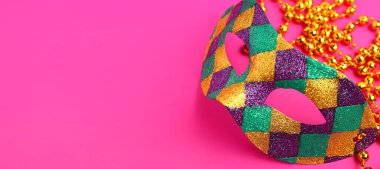 Pembe arkaplandaki karnaval maskesi ve boncukları metin için yer açıyor.