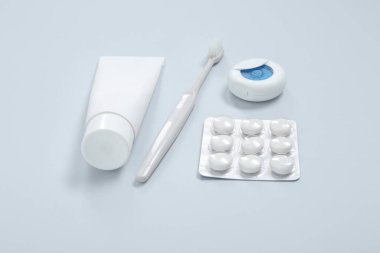 Diş fırçası, diş ipi ve gri arka planda diş eti.