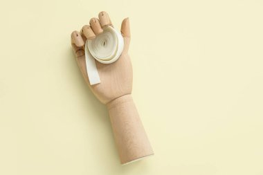 Açık sarı arka planda sakız çiğneyen tahta elli.