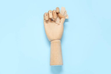 Mavi arka planda sakız çiğneyen tahta bir el.