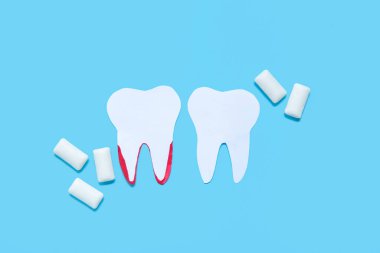 Kağıt dişler ve mavi arka planda beyaz diş etleri.