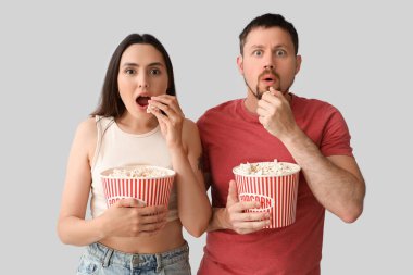 Şok olmuş genç çift arka planda patlamış mısır yiyor.