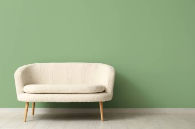 Yeşil duvarın yanındaki rahat beyaz kanepe