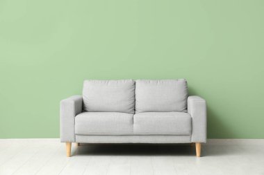 Yeşil duvarın yanındaki rahat gri kanepe