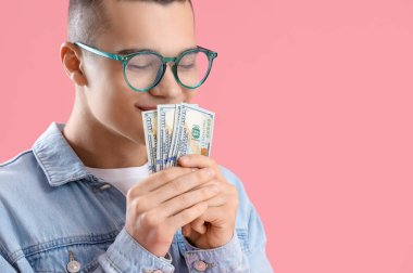 Pembe arka planda dolar banknotları olan genç adam, yakın plan.
