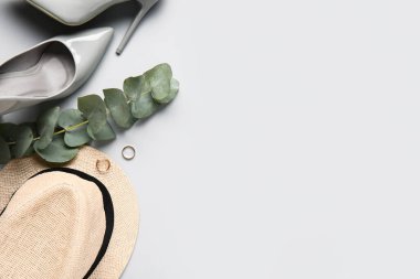 Hafif arka planda şık kadın aksesuarları, ayakkabıları ve okaliptüs dallarıyla kompozisyon