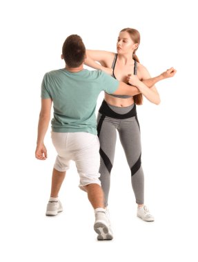 Beyaz arka planda kendini savunma eğitmeniyle kavga eden genç kadın.