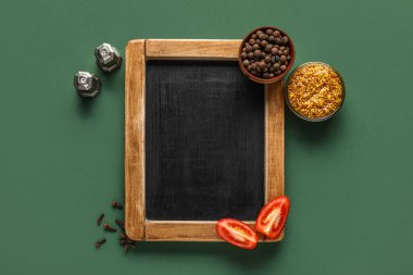 Yeşil zemin üzerinde boş karatahta ve baharatlar olan kompozisyon