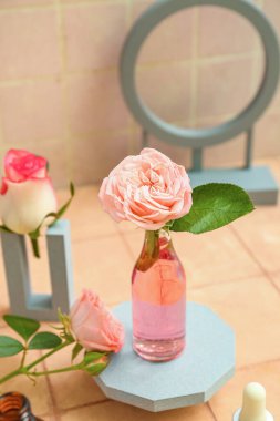 Bej kaplama arka planda gerekli yağ şişesi ve gül çiçeğiyle sıva podyum
