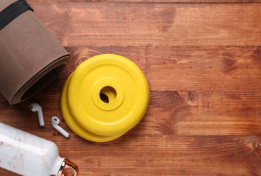 Halter plakası, yoga minderi, su şişesi ve ahşap arka planda kulaklık.