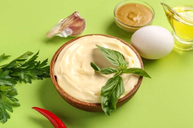 Bir kase taze mayonez ve yeşil arka planda malzemeler.