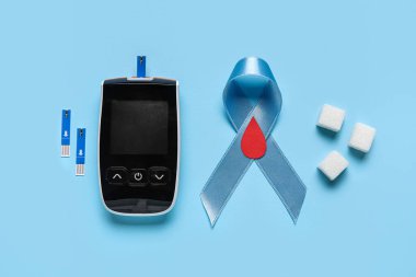 Mavi arka planda şeker küpleri ve glukometreyle farkındalık kurdelesi. Diyabet kavramı
