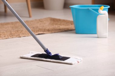 Oturma odasında paspasla ahşap kaplama zemin temizleme, yakın plan.