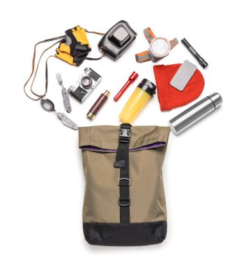 Beyaz arka planda sırt çantası ve açık hava teçhizatı ile yürüyüş için gerekli malzemeler.