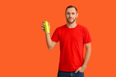 Turuncu arka planda soğuk bira kutusu olan genç adam.