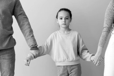 Aydınlık arka planda boşanmış ebeveynleri olan üzgün küçük bir kız.