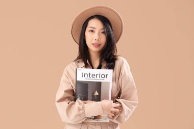 Bej arka planda iç dergisi olan genç Asyalı kadın.