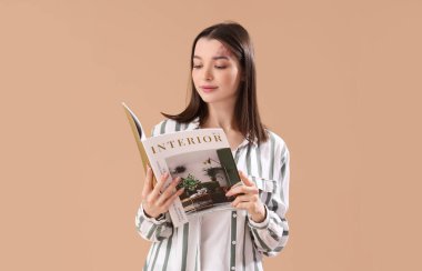 Bej arka planda iç dergi okuyan genç bir kadın.