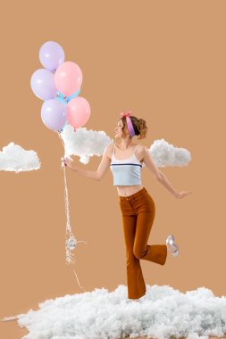 Balonları ve bej arkaplanda beyaz bulutları olan genç bir kadın