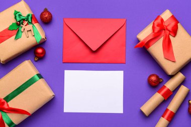 Zarflı boş kağıt, Noel süsü ve mor arka planda hediyeler. Noel Baba 'ya mektup